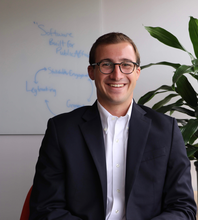 Portrait of Ryan Thornton in Blazer in front of whiteboard that says Software Built for Public Affairs